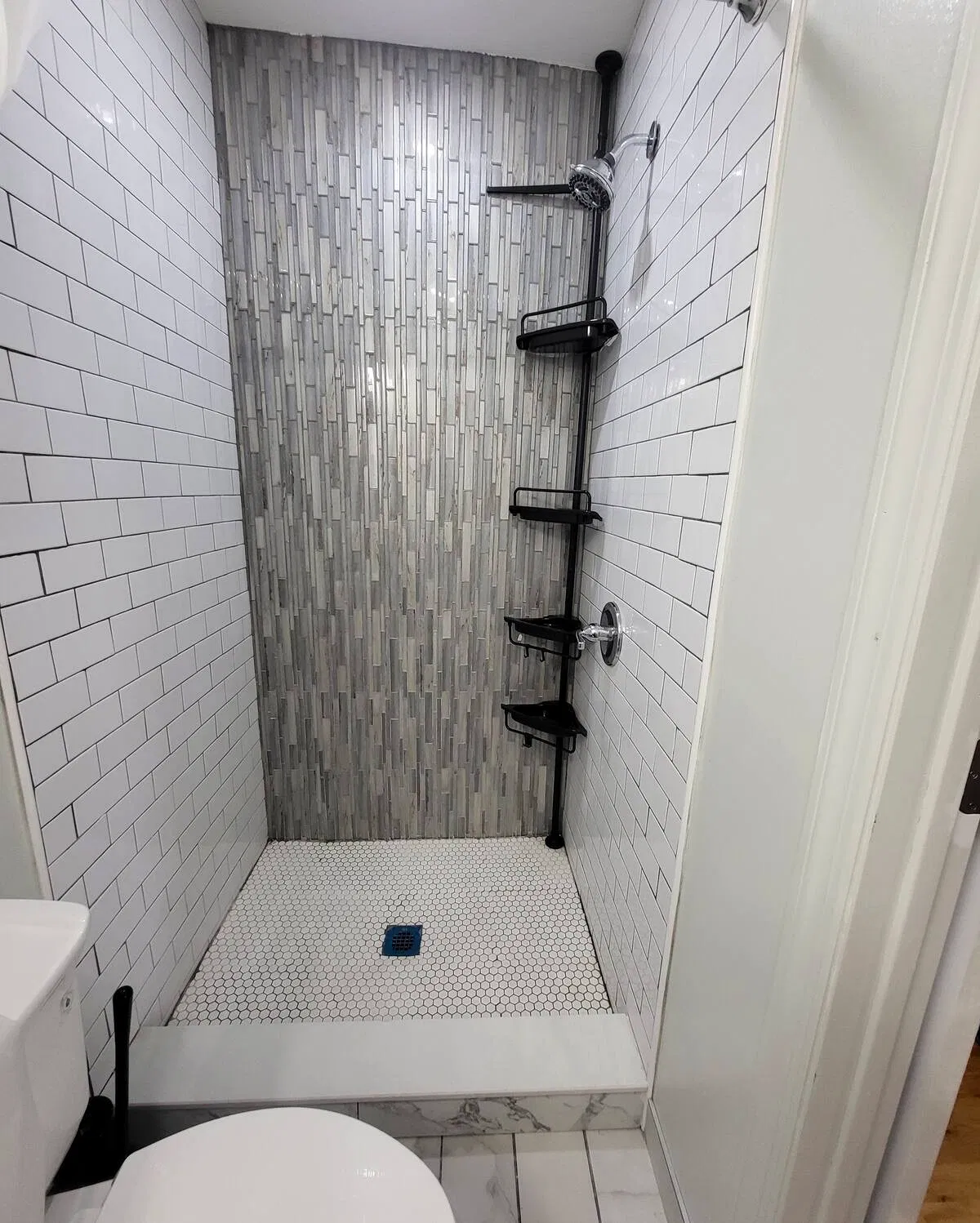 OoohLaLa@Newark — A walk-in shower with contrasting tile finishes and convenient storage shelves.
